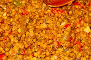 Cooking vegetables with lentils in the pan with wooden spoon, vegan food, seitan.
