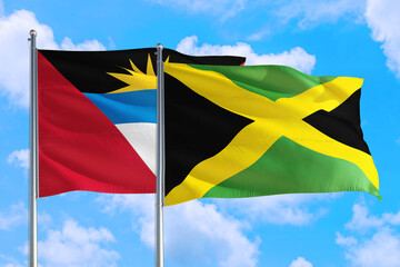 Jamaica and Antigua and Barbuda national flag waving in the windy deep blue sky. Diplomacy and international relations concept.