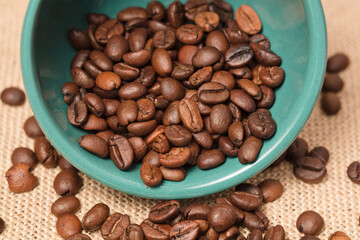 green coffee cup with grains and raffia cloth background
