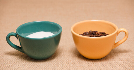 green and yellow coffee cups with grains and sugar, raffia cloth background