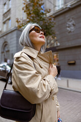 Naklejka premium Mature pale hair stylish woman lifestyle portrait outdoors in city