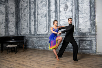 Fototapeta na wymiar beautiful couple with dance costumes dancing latin dances in the hall