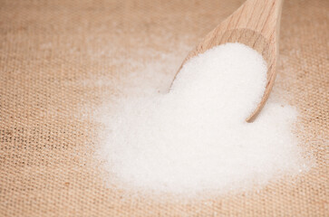 sugar in a wooden spoon,
raffia fabric background