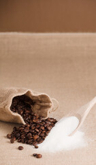 pile of sugar and coffee, wooden spoon and raffia bags, brown background