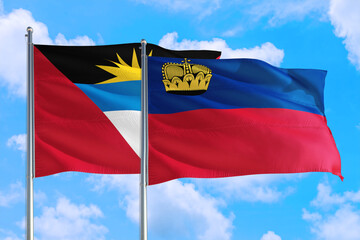 Liechtenstein and Antigua and Barbuda national flag waving in the windy deep blue sky. Diplomacy and international relations concept.