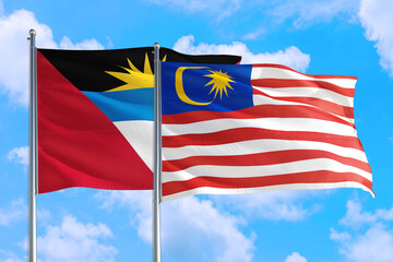 Malaysia and Antigua and Barbuda national flag waving in the windy deep blue sky. Diplomacy and international relations concept.