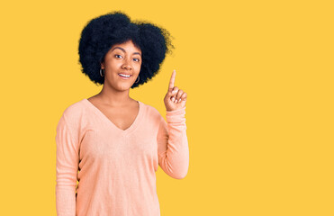 Young african american girl wearing casual clothes showing and pointing up with finger number one while smiling confident and happy.
