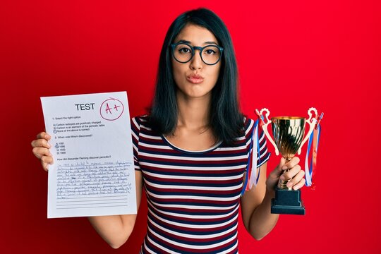 Beautiful Asian Young Woman Showing A Passed Exam Holding Trophy Looking At The Camera Blowing A Kiss Being Lovely And Sexy. Love Expression.