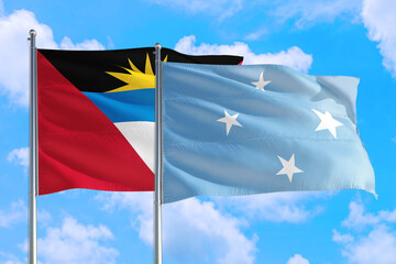 Micronesia and Antigua and Barbuda national flag waving in the windy deep blue sky. Diplomacy and international relations concept.