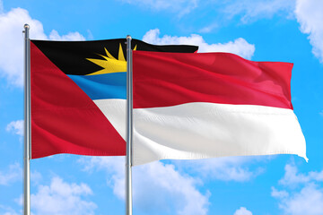 Monaco and Antigua and Barbuda national flag waving in the windy deep blue sky. Diplomacy and international relations concept.
