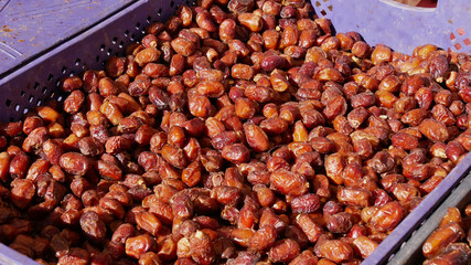 Closeup view of freshly picked date fruits (date palm, phoenix dactylifera) offered for sale in a purple colored box on a Berber market in Imilchil, Morocco, Africa.