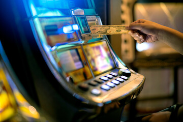Slot Machine Play Time. Female Gambler Hand hold money bill ready to win the game with one best...