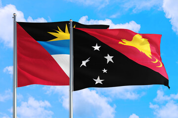 Papua New Guinea and Antigua and Barbuda national flag waving in the windy deep blue sky. Diplomacy and international relations concept.