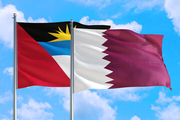 Qatar and Antigua and Barbuda national flag waving in the windy deep blue sky. Diplomacy and international relations concept.