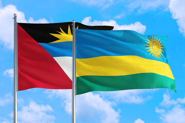 Rwanda and Antigua and Barbuda national flag waving in the windy deep blue sky. Diplomacy and international relations concept.
