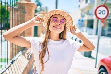 Young beautiful blonde caucasian woman smiling happy outdoors on a sunny day wearing summer hat and...
