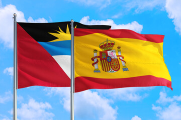 Spain and Antigua and Barbuda national flag waving in the windy deep blue sky. Diplomacy and international relations concept.