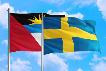 Sweden and Antigua and Barbuda national flag waving in the windy deep blue sky. Diplomacy and international relations concept.