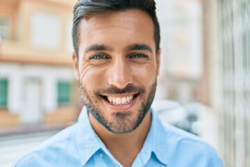 Young hispanic man smiling happy standing at street of city.