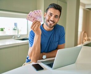 Young handsome man smiling happy holding mexican pesos banknotes at home - obrazy, fototapety, plakaty