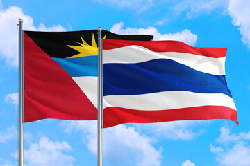 Thailand and Antigua and Barbuda national flag waving in the windy deep blue sky. Diplomacy and international relations concept.