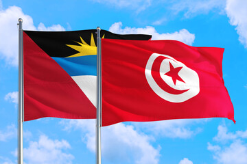 Tunisia and Antigua and Barbuda national flag waving in the windy deep blue sky. Diplomacy and international relations concept.