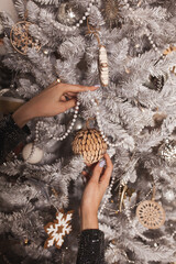 Cropped hand of woman decorating and hanging baubles on Christmas tree.Christmas tree background image
