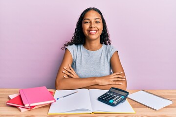 Young african american girl accountant working at the office happy face smiling with crossed arms looking at the camera. positive person.