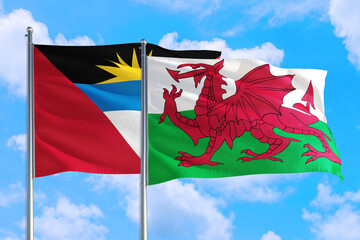 Wales and Antigua and Barbuda national flag waving in the windy deep blue sky. Diplomacy and international relations concept.
