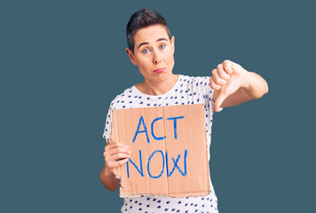Young woman with short hair holding act now banner with angry face, negative sign showing dislike...