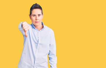 Young woman with short hair wearing business clothes looking unhappy and angry showing rejection and negative with thumbs down gesture. bad expression.