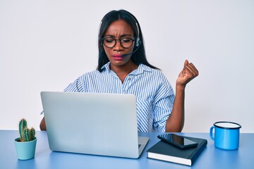 Young african american woman working at the office wearing operator headset annoyed and frustrated shouting with anger, yelling crazy with anger and hand raised