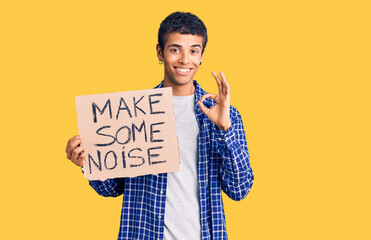 Young african amercian man holding make some noise banner doing ok sign with fingers, smiling friendly gesturing excellent symbol
