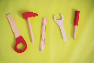 Toy tools on a green background. Hammer, ruler, wrench, screwdriver, saw. Working equipment