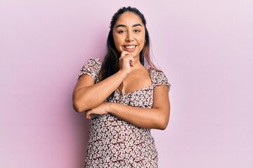 Young latin woman wearing casual clothes looking confident at the camera with smile with crossed arms and hand raised on chin. thinking positive.