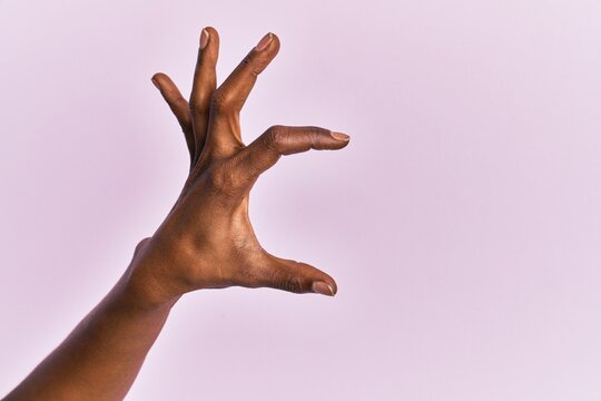 Arm and hand of black middle age woman over pink isolated background picking and taking invisible thing, holding object with fingers showing space