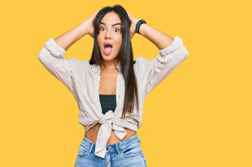 Young beautiful hispanic girl wearing casual clothes crazy and scared with hands on head, afraid and surprised of shock with open mouth