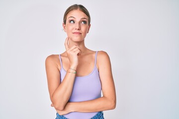 Young blonde girl wearing casual style with sleeveless shirt thinking concentrated about doubt with...
