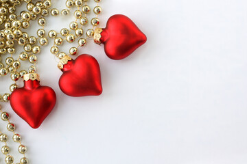  Red hearts and gold beads on a white background. Decorations for the New Year tree.  There is room for text. Christmas card.