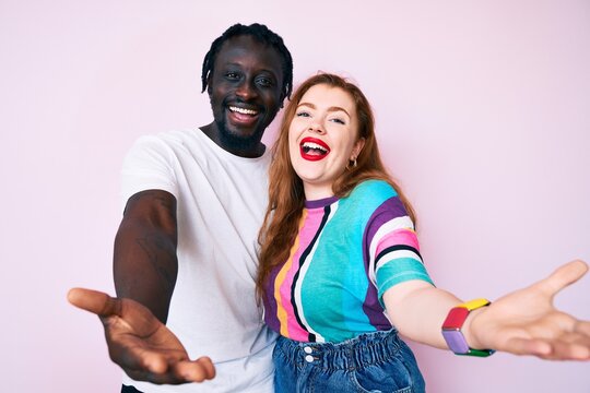 Interracial couple wearing casual clothes smiling cheerful offering hands giving assistance and acceptance.