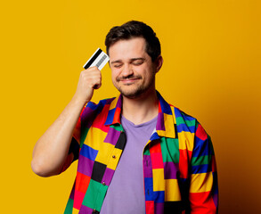 style guy in 90s shirt with credit card on yellow background