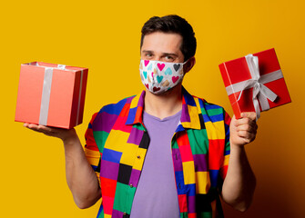style guy in 90s shirt and face mask with gift box on yellow background