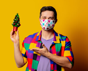 style guy in 90s shirt and face mask with Christmas tree on yellow background