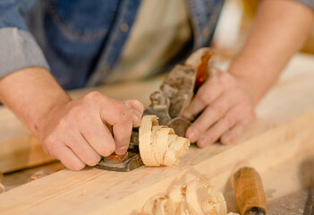 Hands of a carpenter planed wood in a workshop