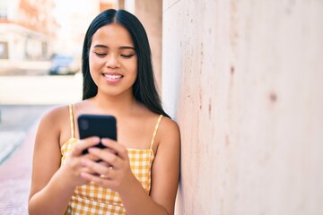 Young asian girl smiling happy at the city using smartphone