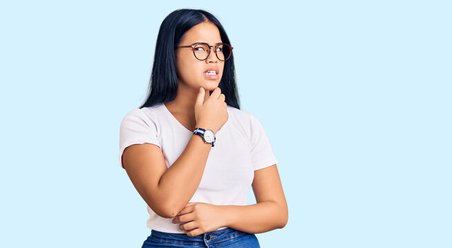 Young beautiful asian girl wearing casual clothes and glasses thinking worried about a question, concerned and nervous with hand on chin