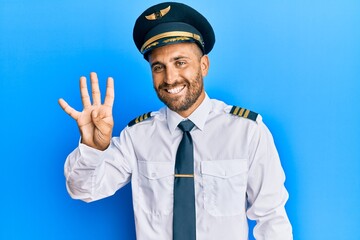 Handsome man with beard wearing airplane pilot uniform showing and pointing up with fingers number four while smiling confident and happy.
