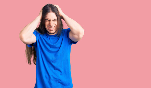 Young adult man with long hair wearing swimwear suffering from headache desperate and stressed because pain and migraine. hands on head.