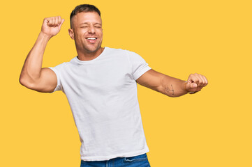 Naklejka premium Handsome muscle man wearing casual white tshirt dancing happy and cheerful, smiling moving casual and confident listening to music