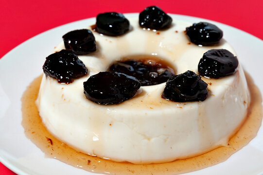 Delicious traditional Brazilian dessert known as "Manjar de Coco Branco" with plum sauce. Traditionally consumed at Christmas and New Year in Brazil. Isolated on red background. Close-up.